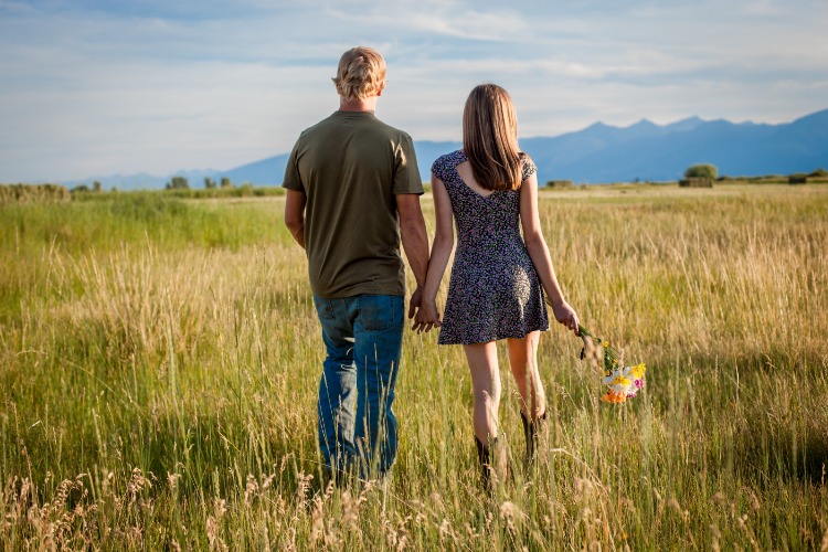 Young couple walking through a pasture on a summer day